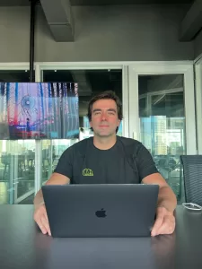 Homem branco, sentado em frente a frente um computador